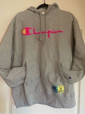 Champion Reverse Weave Gray Hoodie Fuschia Chenille Logo with Blue Trim border.